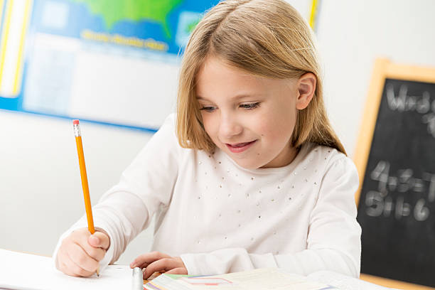 bambino di scuola elementare in aula - reading and writing blackboard book elementary school building foto e immagini stock