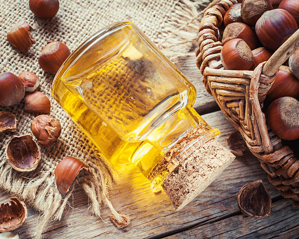 Bottle of nut oil and basket with filberts on  table. Bottle of nut oil and basket with filberts on old kitchen table. Top view. hazel tree stock pictures, royalty-free photos & images