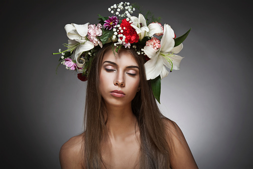 Beautiful woman with flower wreath on black background