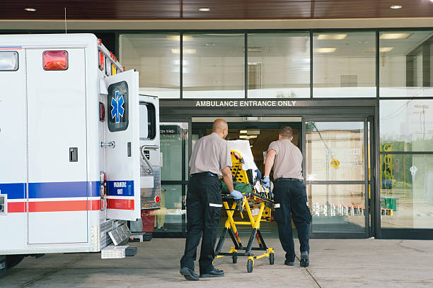 Paramedics taking patient on stretcher from ambulance to hospital stock photo