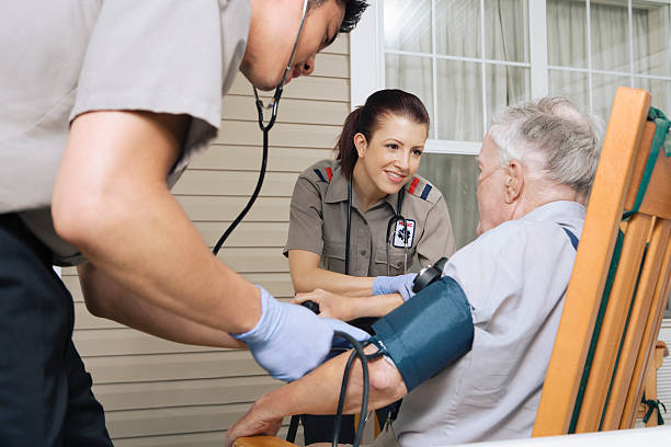 Paramedics examining senior man on porch