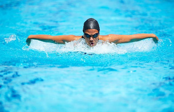 Focussed on bettering her time A focused young female swimmer doing the butterfly stroke women exercising swimming pool young women stock pictures, royalty-free photos & images