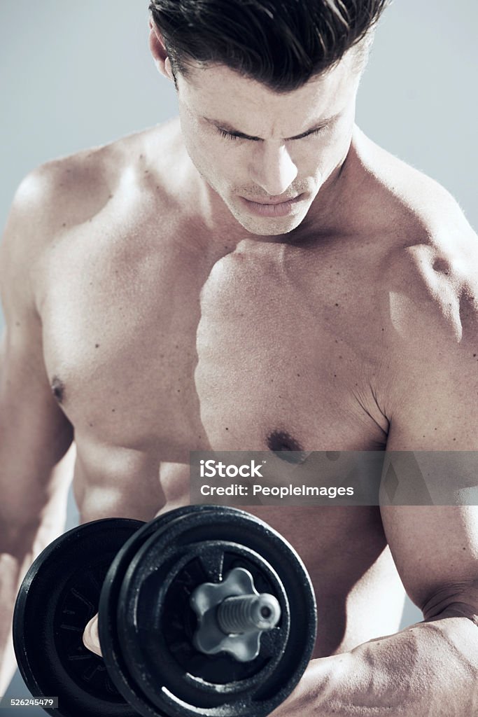 Pumping iron Shot of a handsome young man lifting weights Abdomen Stock Photo