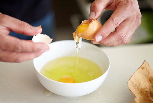Cropped image of a man breaking an egg into a bowl