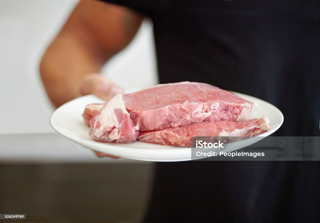 Ensuring his diet contains enough protein Cropped image of a muscular man holding a plate of raw beef Adult Stock Photo