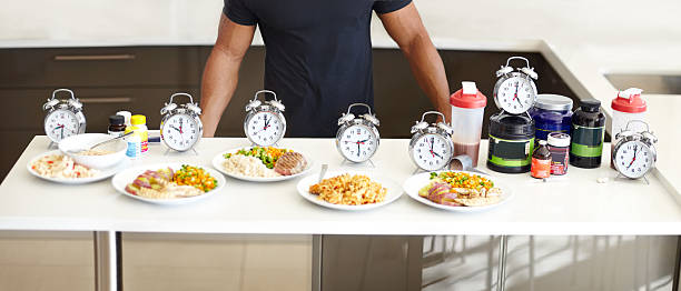 Balanced meals with structured mealtimes is a must Cropped view of a man standing behind his perfectly structured daily food intake food with clock 