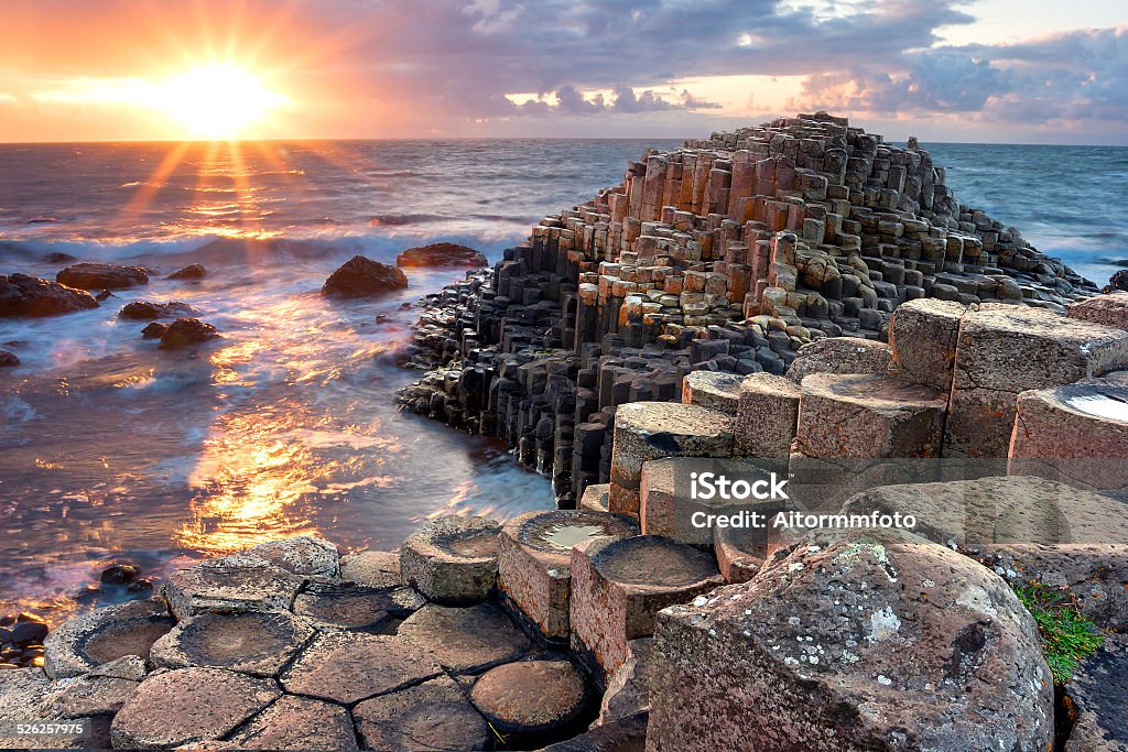 Sunset at Giants causeway People visiting Giant s Causeway at the sunset in North Antrim, Northern Ireland Giants Causeway Stock Photo