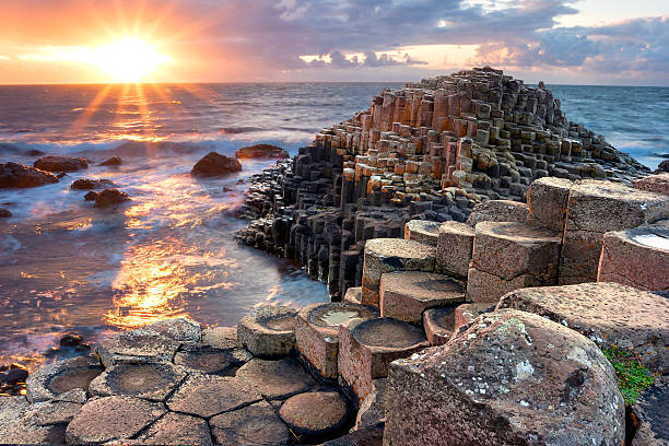 Sunset at Giants causeway People visiting Giant s Causeway at the sunset in North Antrim, Northern Ireland ireland photos stock pictures, royalty-free photos & images