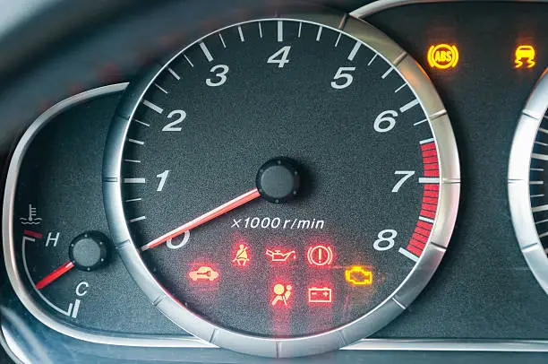 Closeup of car tachometer with many illuminated indicators