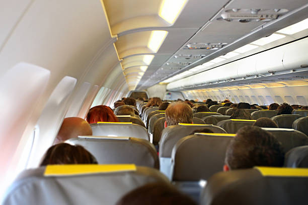 istock Airplane cabin interior with rows of passengers sitting 526262675