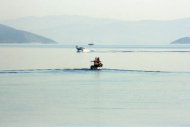 Detail of tied-up or moored fishing boat in the harbor (or harbour) of the small fishing village of Agia Ermioni at the eastern coastline of the Greek Island of Chios in the Aegean Sea on a sunny midday in spring (late March). In the background is the Turkish coastline. The image was captured on old-fashioned 35mm daylight ISO 200 film by an analogue (or analog) 35 mm film camera. The granularity in the image is real film grain (due to the presence of small particles of dyed silver halide on the negative). Minimal post processing has been done (only adjustment of histogram). The image is part of a series of a harbour (or harbor) on the Greek Island of Chios.