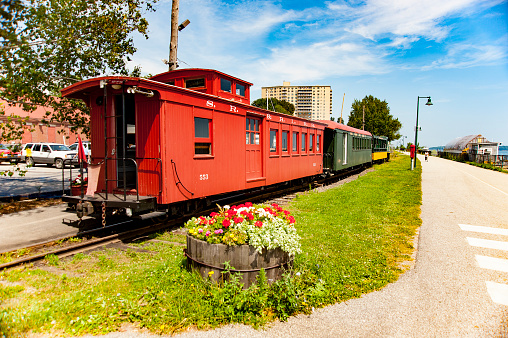 Portland, Maine, USA - August 10, 2009: Working train from Maine Narrow Gauge Railroad Co & Museum lined up along Eastern Promenade Trail on Casco Bay