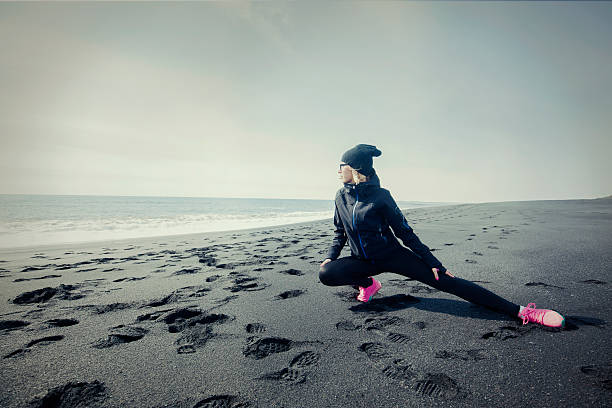 corte jovem mulher alongamentos a perna depois do trabalho para fora - stretch beach imagens e fotografias de stock