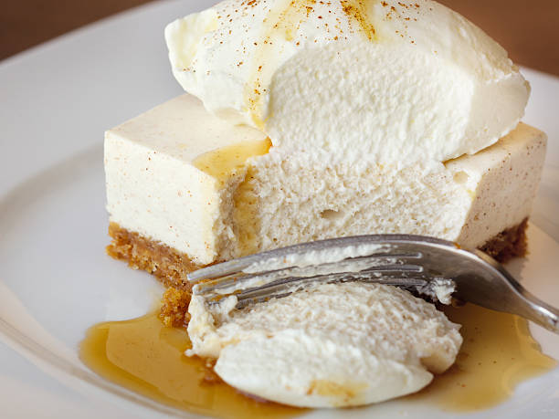 Brightly lit studio photo of freshly made cheesecake with whipped cream and caramel