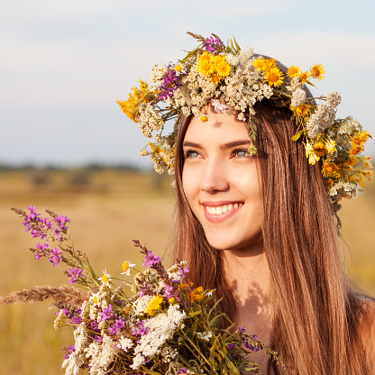 Portrait of young beautiful cute romantic  girl wearing a wreath of wild flowers in summer day, outdoors. Happy woman. Series of photos