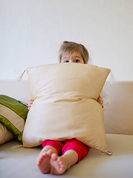 istock cute girl hiding behind pillow 526284062