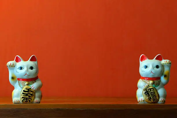The maneki-neko (Japanese: 招き猫?, literally "beckoning cat") is a common Japanese figurine (lucky charm, talisman) which is often believed to bring good luck to the owner. In modern times, they are usually made of ceramic or plastic. The figurine depicts a cat (traditionally a calico Japanese Bobtail) beckoning with an upright paw, and is usually displayed—often at the entrance—of shops, restaurants, pachinko parlors, and other businesses. Some of the sculptures are electric or battery-powered and have a slow-moving paw beckoning. The maneki-neko is sometimes also called the welcoming cat, lucky cat, money cat, happy cat, beckoning cat, or fortune cat in English.