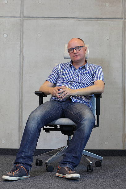 istock middle age balding man bad sitting position on chair 526285997