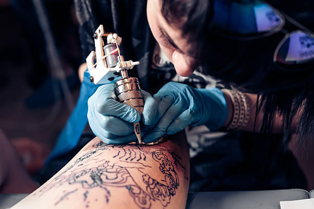 Tattoo artist demonstrates the process of tattoo Close up tattoo artist demonstrates the process of getting black tattoo with paint. Master works in black sterile gloves. Master of tattoo fill circuit tattoo. tattooing stock pictures, royalty-free photos & images