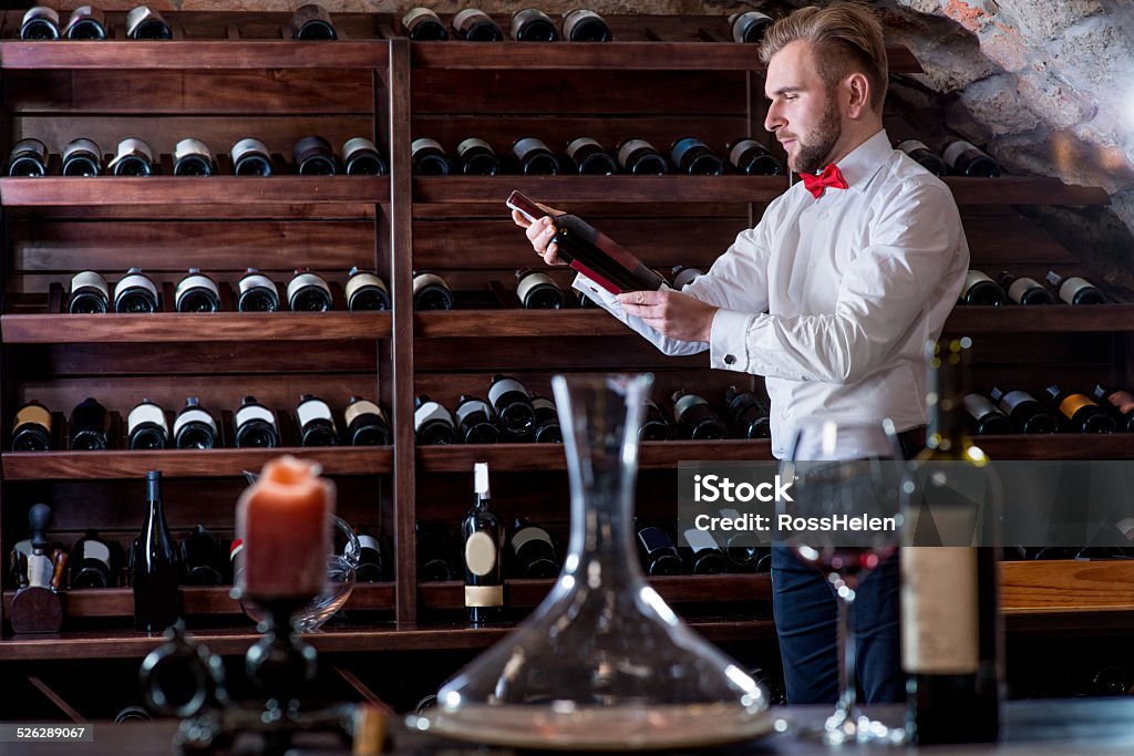 Sommelier in the wine cellar Sommelier looking for good wine on the storage in the wine cellar Sommelier Stock Photo