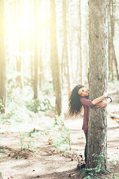 istock Beautiful young woman hugging a tree in the sunny forest 526289330
