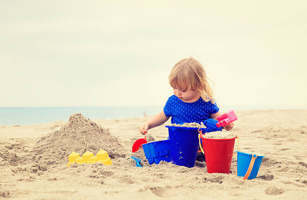 istock little girl play with sand on beach 526295104