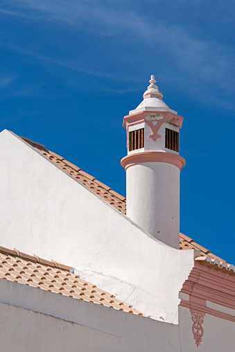 Traditional Portugese rooftop chimney against a clear blue sky.