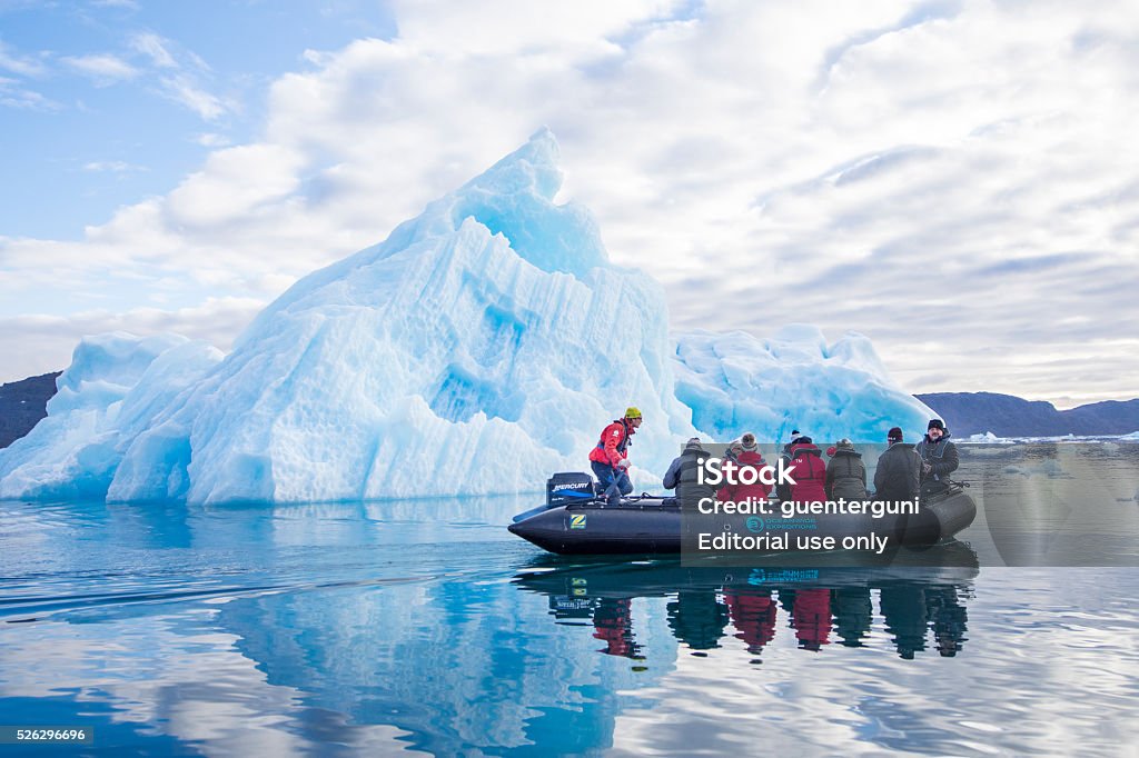 Tourists in a Zodiac in front of an iceberg, Greenland Bredefjord, Greenland - October 10, 2015: Group of tourists on an excursion in a Zodiac boat in front of a bizarre shaped Iceberg in the arctic sea; Southern Greenland. Arctic Stock Photo