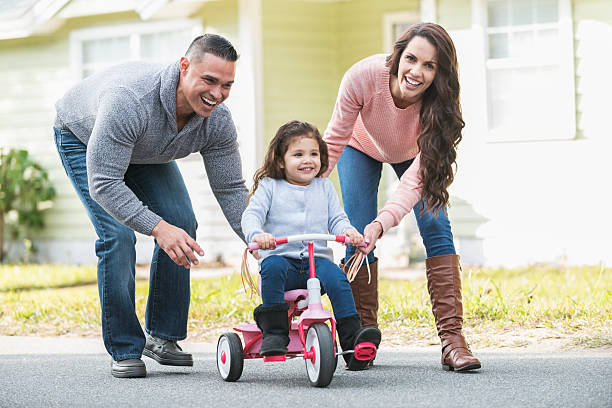 istock Hispanic parents helping girl ride tricycle 526297766