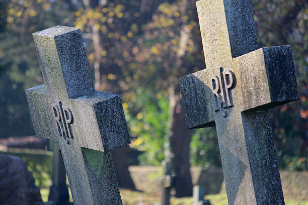 istock Old cross-shaped granite RIP gravestones / crosses, church cemetery graveyard, leaning 526308793