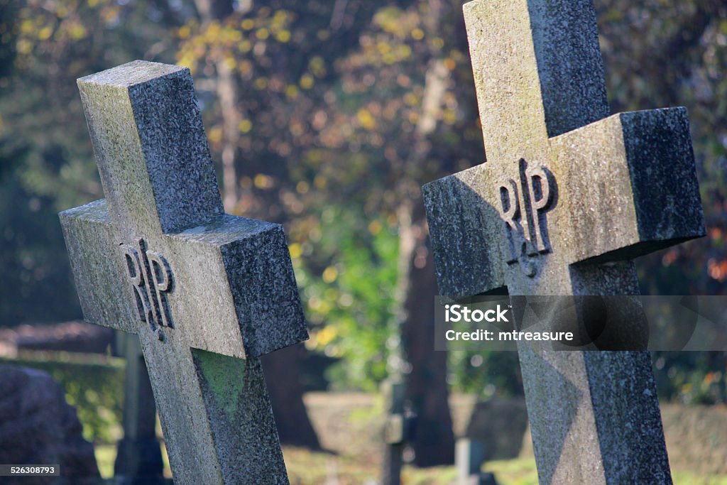 Old cross-shaped granite RIP gravestones / crosses, church cemetery graveyard, leaning Photo showing a number of large cross shaped RIP gravestones made from granite, pictured in a church cemetery.  The gravestones are many years old and are well weathered with lichen and moss.  The graveyard is rather neglected and rundown and the stone crosses are clearly starting to lean precariously, becoming unstable and being in danger of falling over in the future. Brick Stock Photo