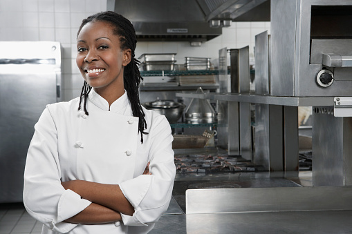 Portrait of a smiling female chef with hands crossed in the kitchen