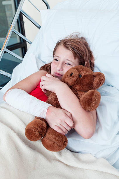 little girl holding osito de peluche en cama de hospital - child physical injury teddy bear wound fotografías e imágenes de stock