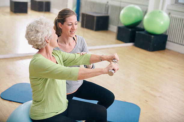 istock Senior woman assisted by personal trainer in gym 526312151