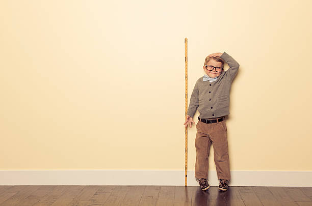 young boy nerd measures height and is tall - kort längd bildbanksfoton och bilder