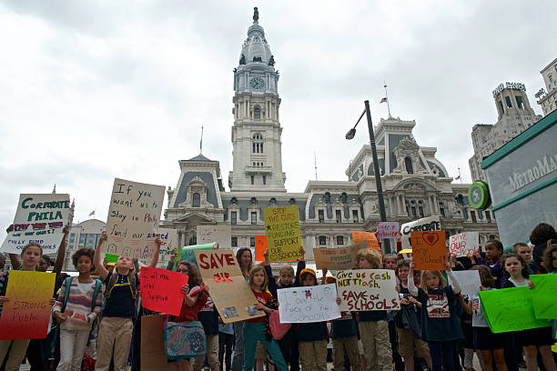 Philadelphia Education Funding Protests Philadelphia, PA USA - May 15, 2013; A small group of young students and parents from Northwest Philadelphia participate in a 'walk-out' to protest the way the local public school system is funded. Signs are carried as they join others in a protest at Philadelphia City Hall (seen in the background). (photo by Bas Slabbers) superintendent stock pictures, royalty-free photos & images