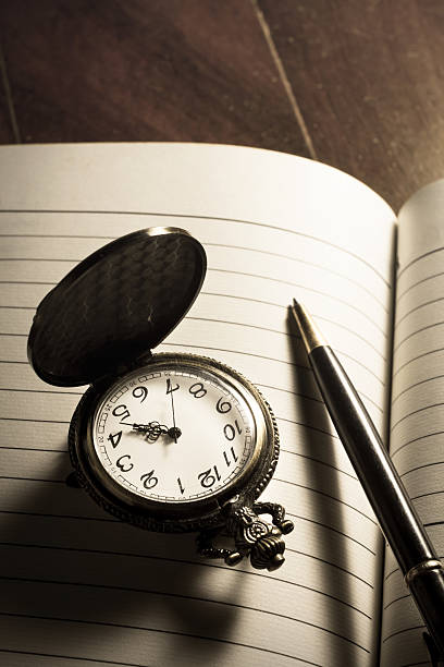 istock Pocket watch and pen on book. 526324995