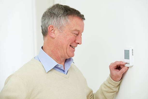 istock Senior Man Adjusting Central Heating Thermostat 526325059