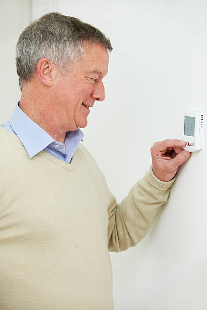 istock Senior Man Adjusting Central Heating Thermostat 526325063