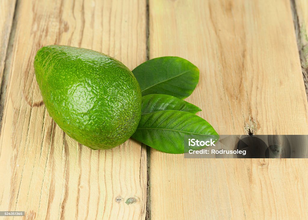 Ripe Green Avocado with Leaves on Wooden Background. Ripe Green Avocado with Leaves on Wooden Background. Closeup. Avocado Stock Photo