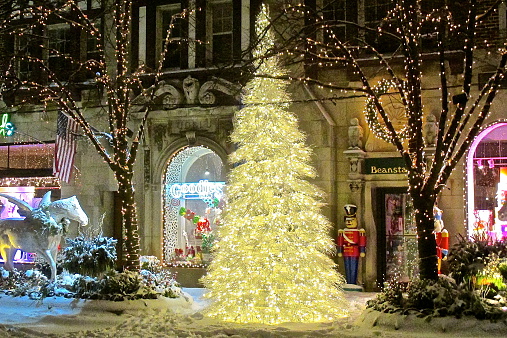 HIghland Park, IL, USA - December 8, 2013: A Christmas tree, holiday season lights, decorations, and some snow downtown on a winter night. 