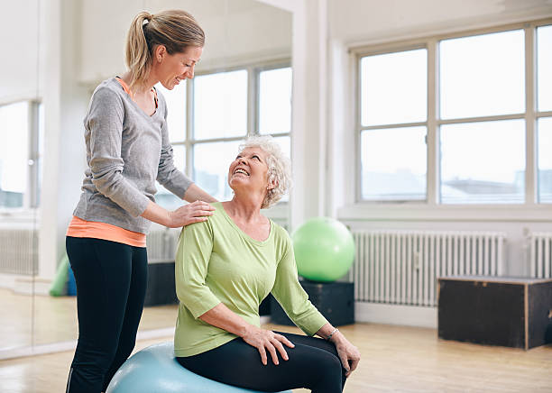 istock Older woman assisted by personal trainer at gym 526354923
