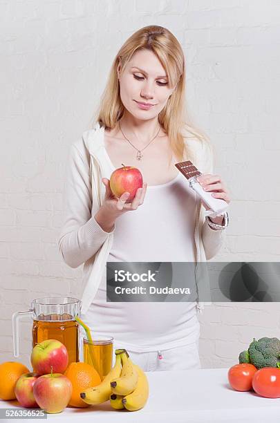Pregnant Woman Choosing Between Apple And Chocolate Stock Photo - Download Image Now