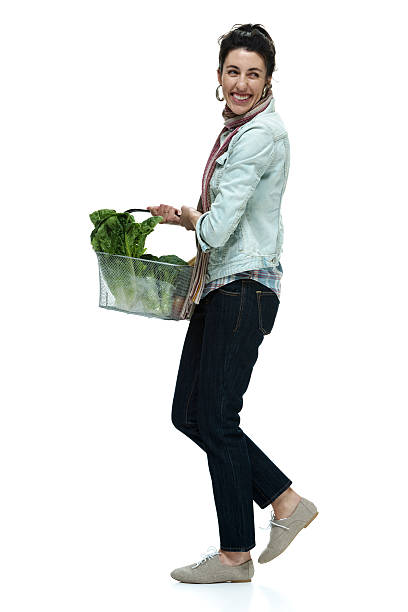 istock Cheerful woman holding vegetable basket & walking 526356749
