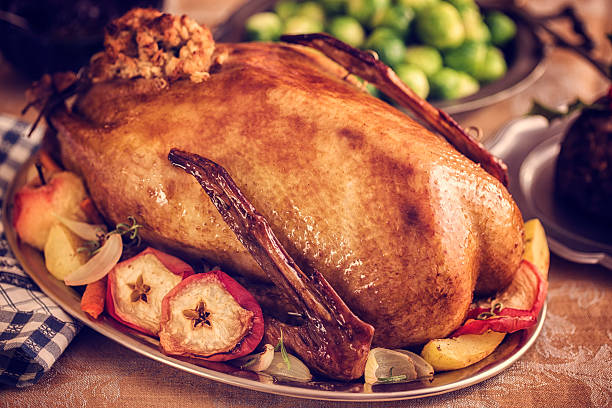 tradicional británica holiday ánsar la cena con manzanas y bruselas sprouts - goose roasted goose meat spit roasted fotografías e imágenes de stock