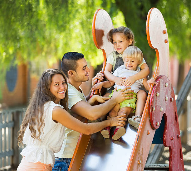 istock Smiling parents helping kids on slide 526373297