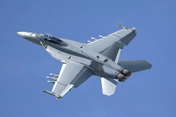 Boeing F/A-18 Super Hornet fighter aircraft manoeuvring through the blue sky whilst loaded with missiles