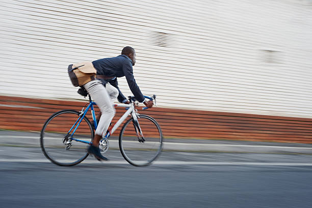 riding bike black man Black african mad riding bicycle in urban city commuting with speed and hipster trendy transportation commuter stock pictures, royalty-free photos & images