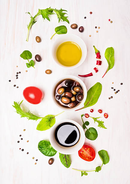 preparazione insalata con condimenti, olive, wild hebs, olio e pomodori - vinegar salad dressing balsamic vinegar olive oil foto e immagini stock