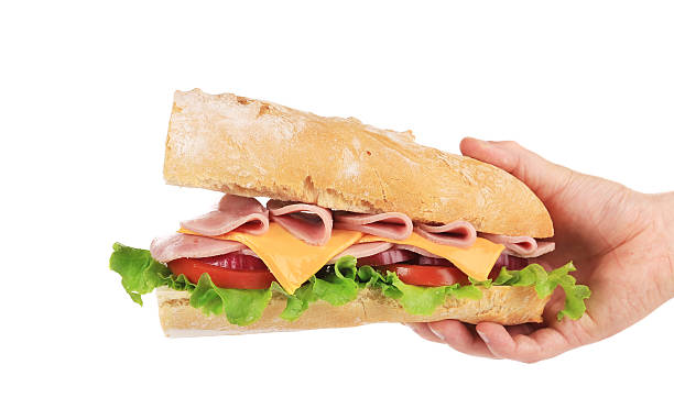 istock Hand holding french baguette sandwich. 526391555